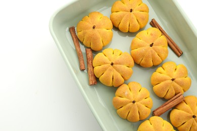 Photo of Baking tray with tasty pumpkin shaped buns and cinnamon sticks on white background, top view. Space for text