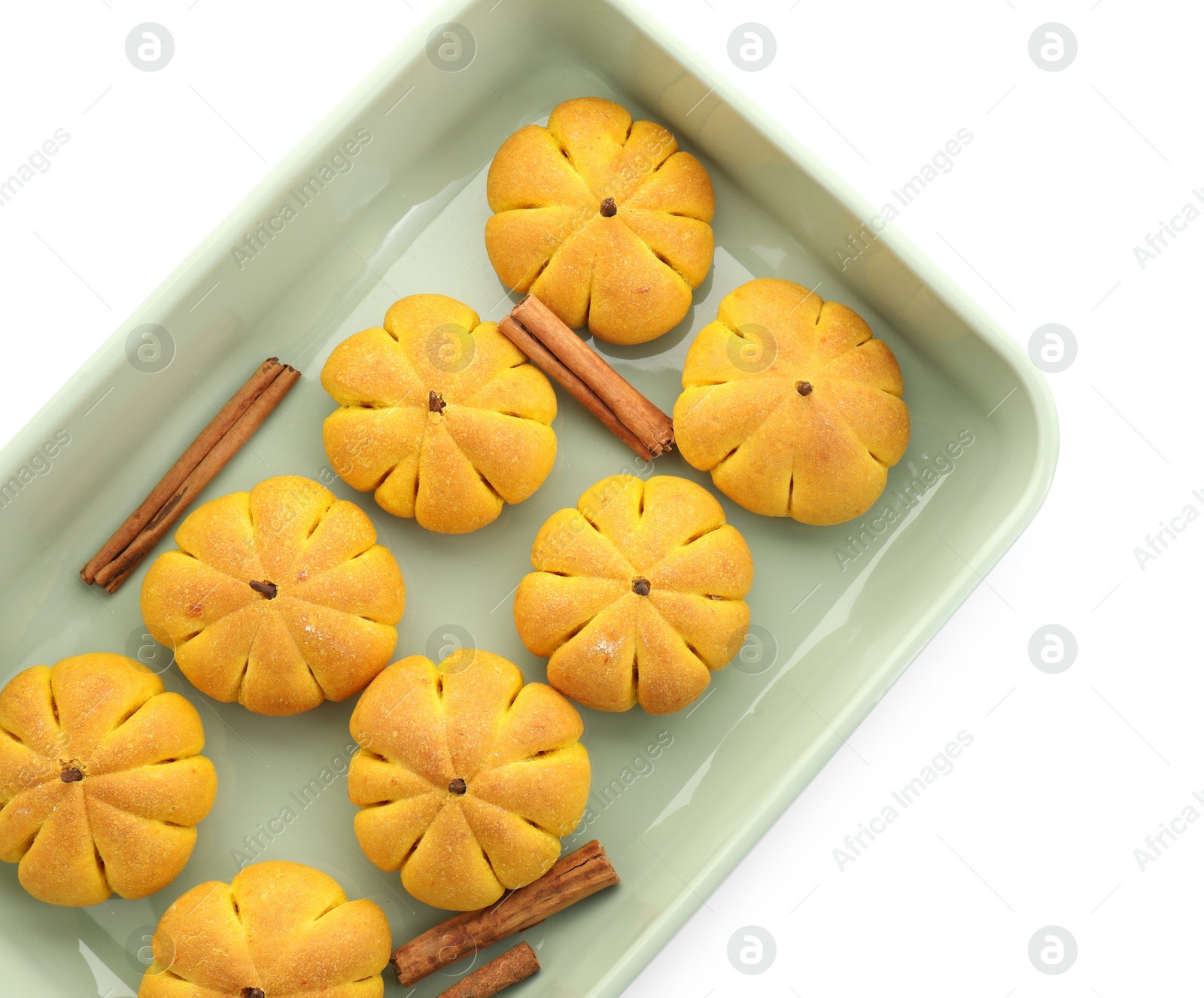 Photo of Baking tray with tasty pumpkin shaped buns and cinnamon sticks isolated on white, top view