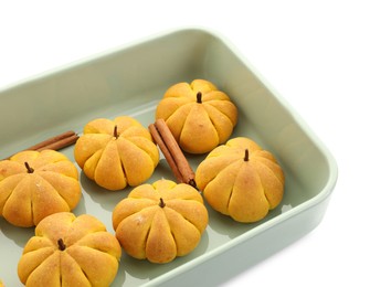 Baking tray with tasty pumpkin shaped buns and cinnamon sticks isolated on white