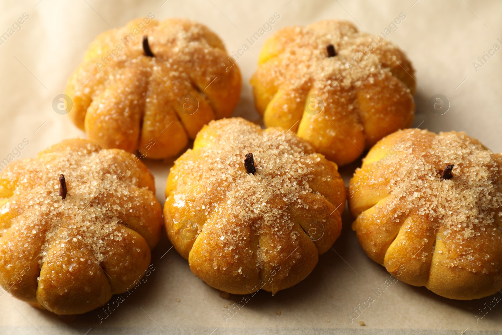 Photo of Tasty pumpkin shaped buns on parchment, closeup