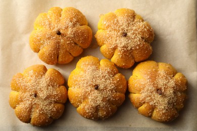 Photo of Tasty pumpkin shaped buns on parchment, top view