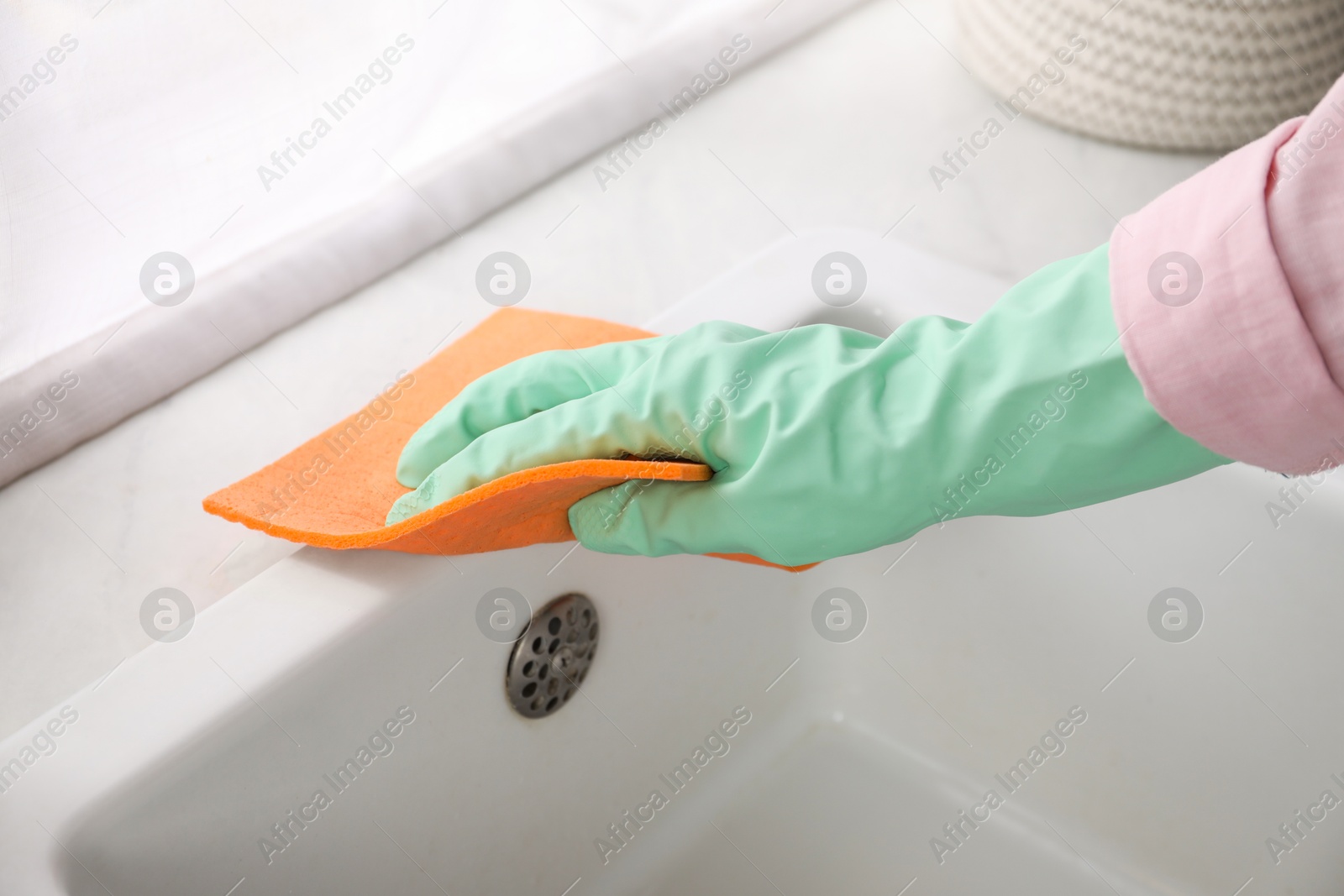 Photo of Woman wiping sink with napkin in kitchen, closeup