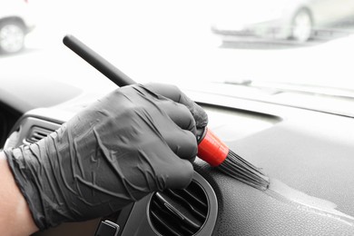 Photo of Man cleaning car interior with brush, closeup