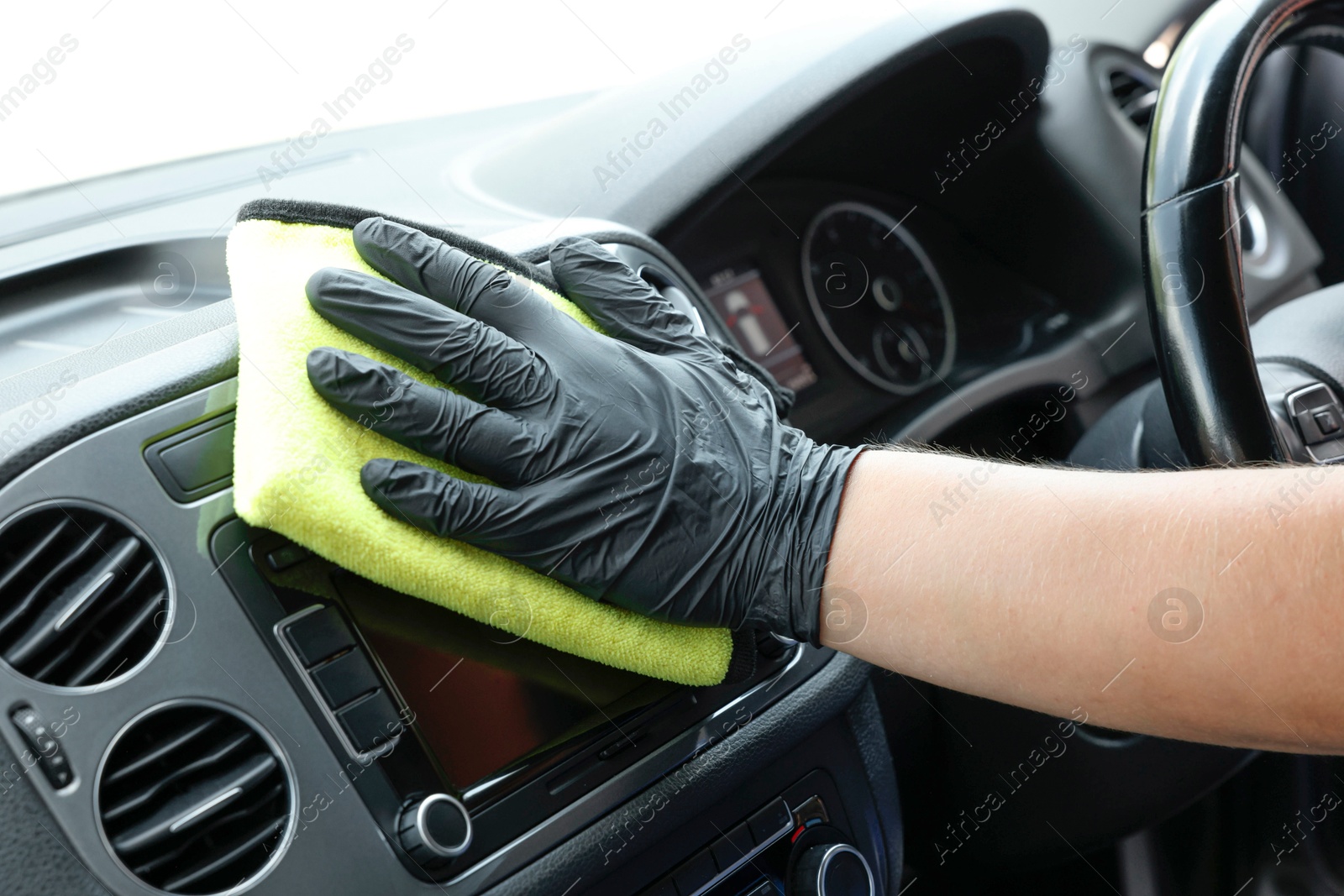 Photo of Man cleaning center console with rag, closeup