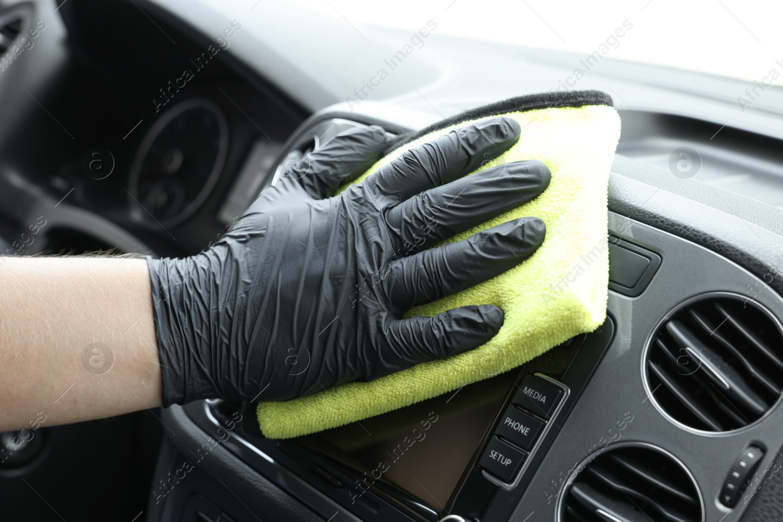 Photo of Man cleaning center console with rag, closeup