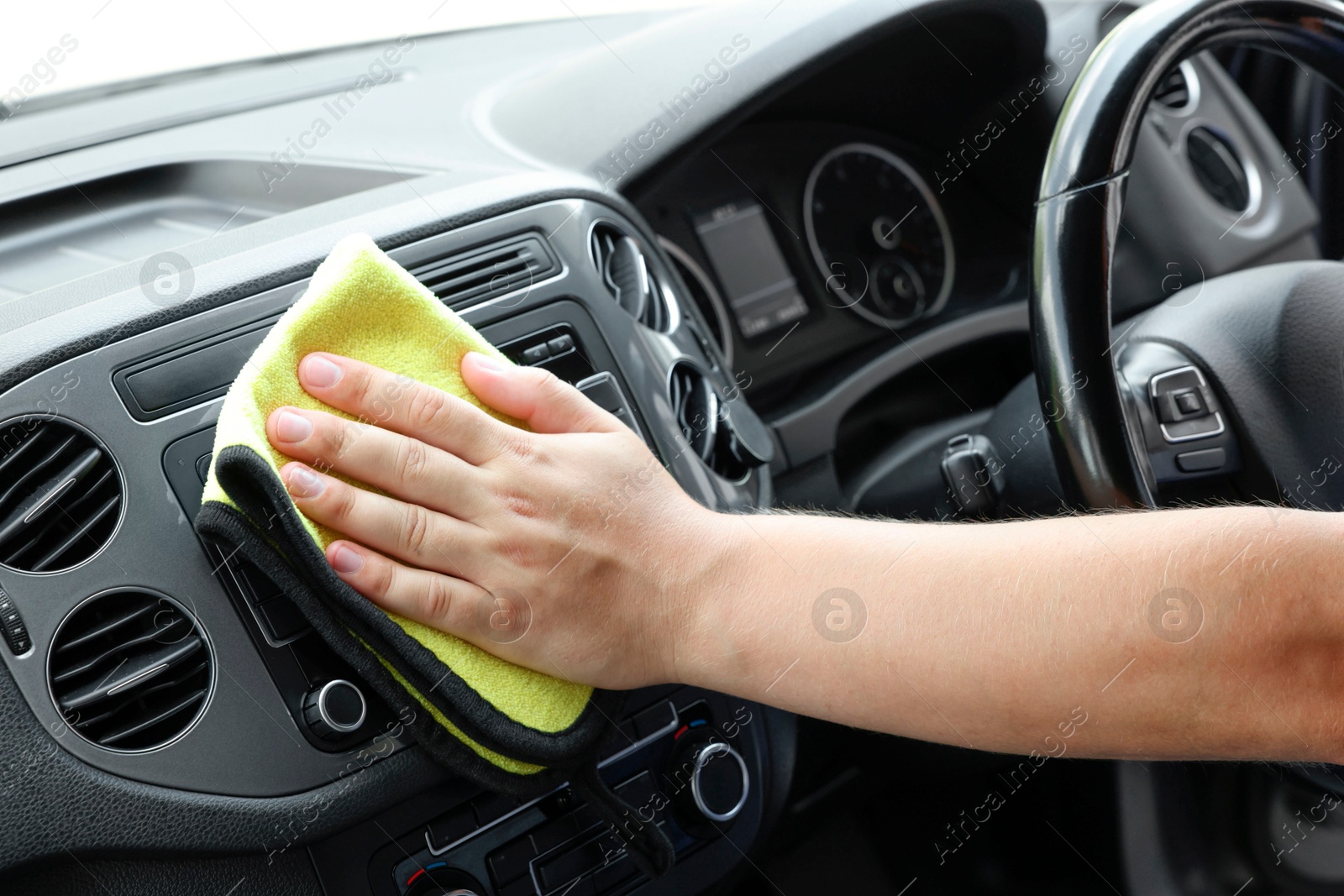 Photo of Man cleaning center console with rag, closeup