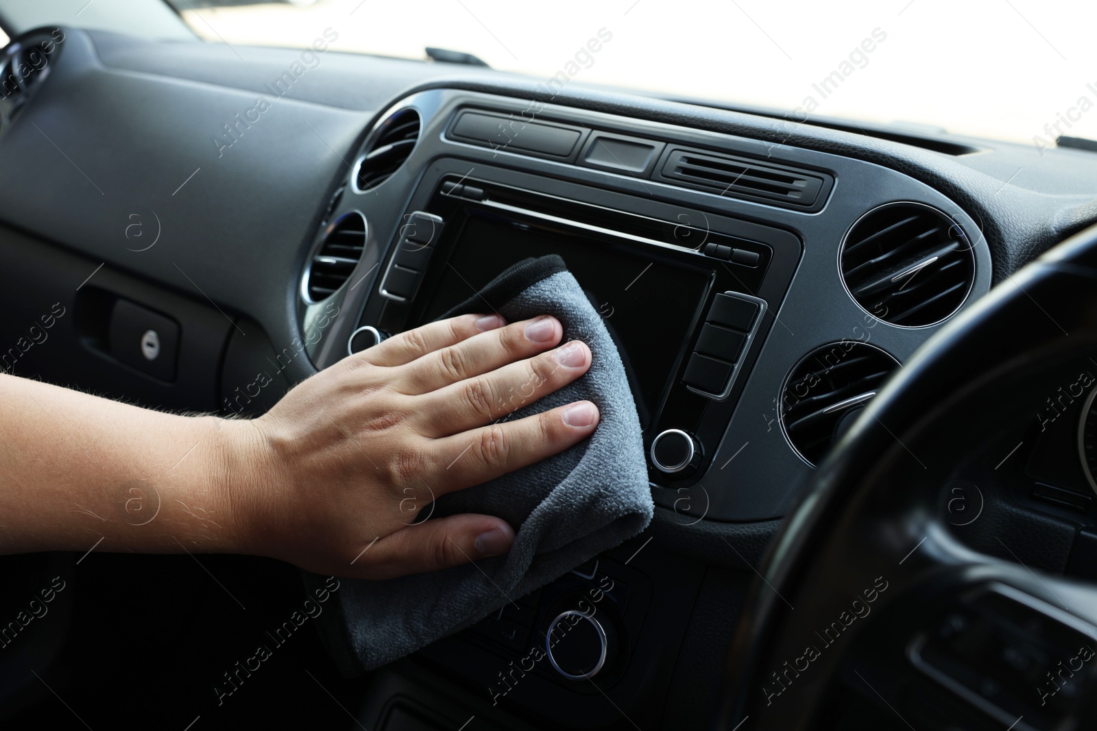 Photo of Man cleaning center console with rag, closeup