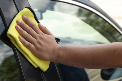 Man wiping car window with yellow rag, closeup