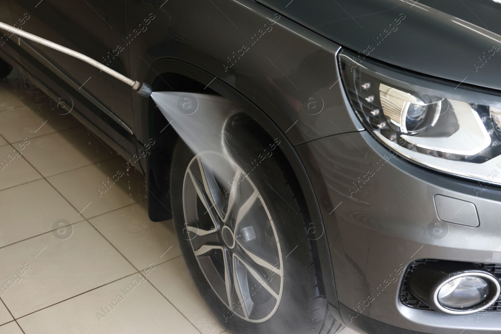 Photo of Washing auto with high pressure water jet at car wash, closeup