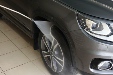 Washing auto with high pressure water jet at car wash, closeup