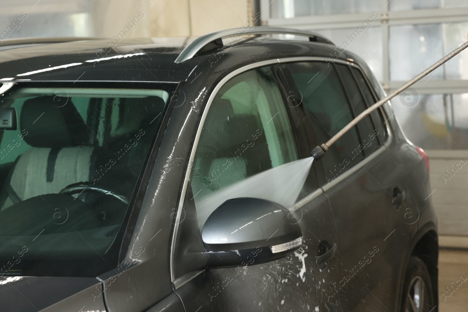 Photo of Washing auto with high pressure water jet at car wash, closeup