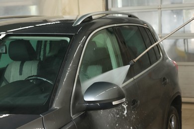 Washing auto with high pressure water jet at car wash, closeup