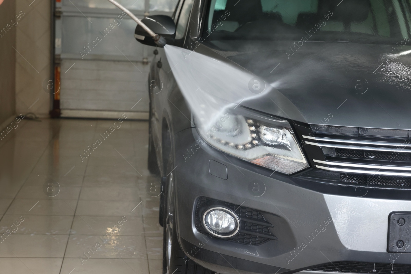 Photo of Washing auto with high pressure water jet at car wash, closeup