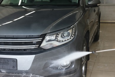 Photo of Washing auto with high pressure water jet at car wash, closeup