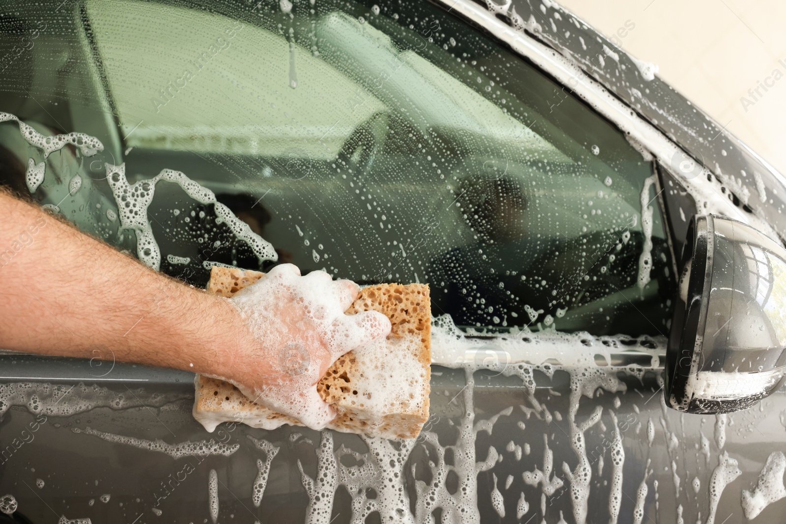 Photo of Man washing auto with sponge at car wash, closeup