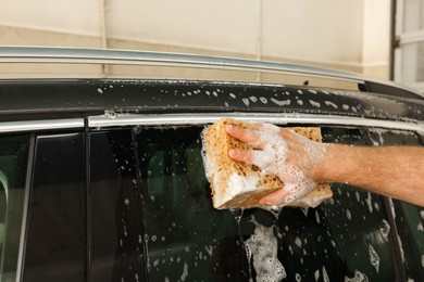 Man washing auto with sponge at car wash, closeup