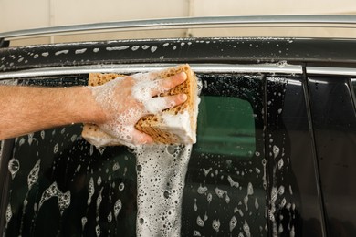 Photo of Man washing auto with sponge at car wash, closeup