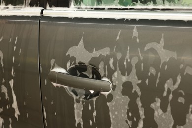 Auto covered with cleaning foam at car wash, closeup