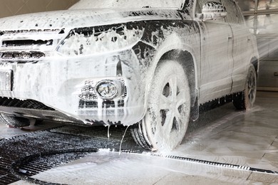 Photo of Washing auto with high pressure water jet at car wash, closeup