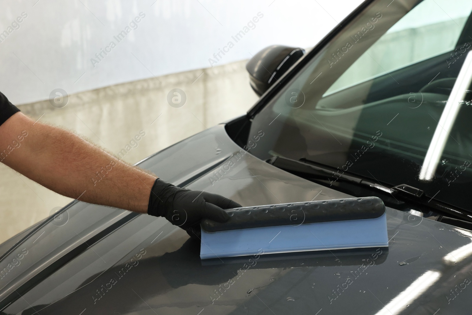 Photo of Man wiping auto with squeegee brush at car wash, closeup