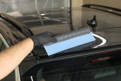 Man wiping auto with squeegee brush at car wash, closeup