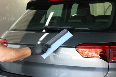 Photo of Man wiping auto with squeegee brush at car wash, closeup