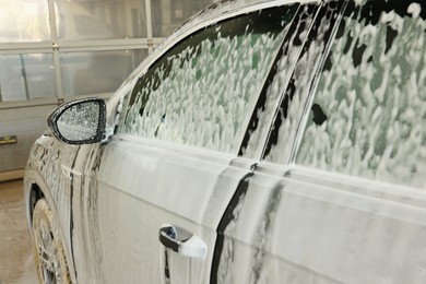 Auto covered with cleaning foam at car wash, closeup