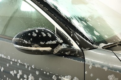 Auto covered with cleaning foam at car wash, closeup