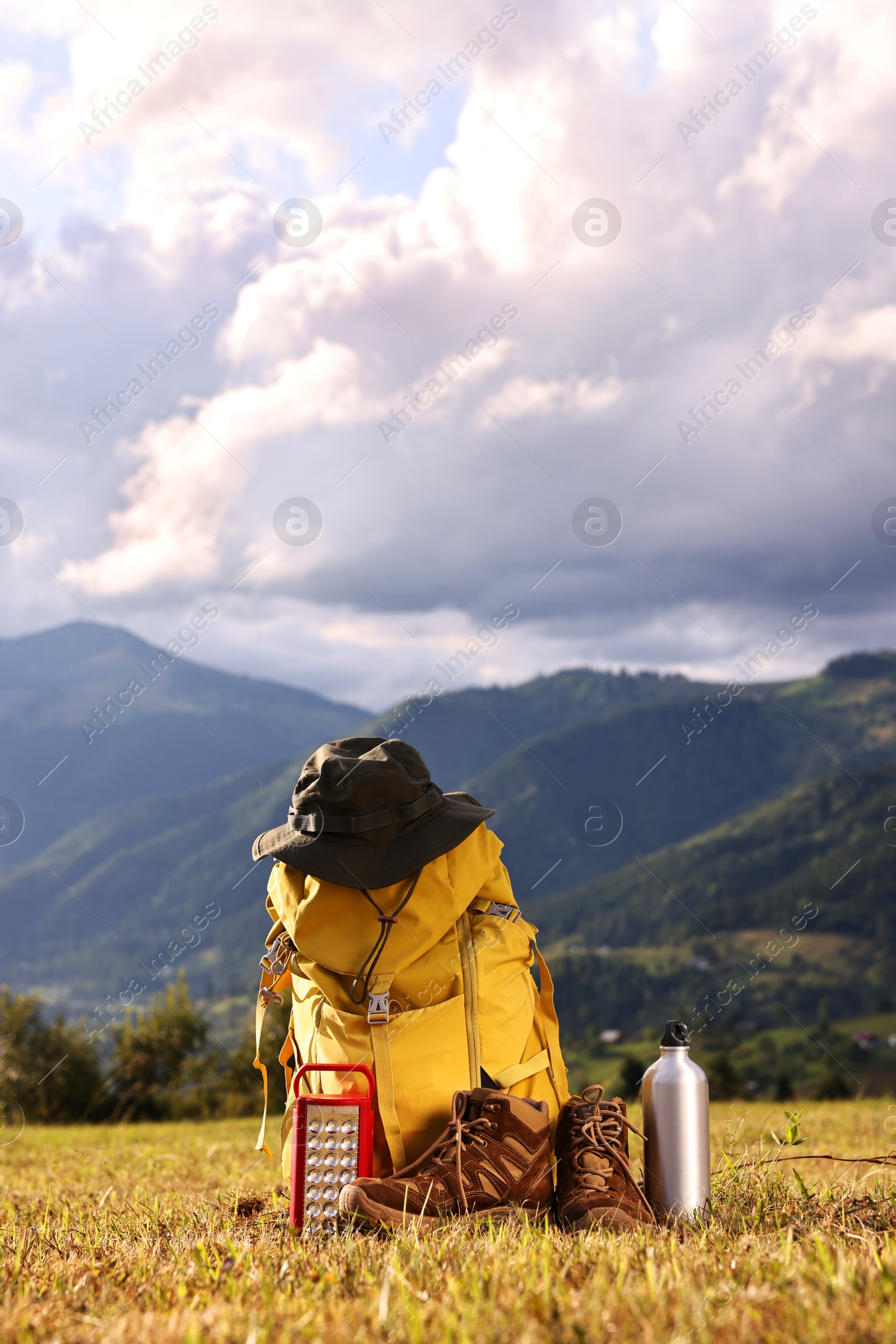 Photo of Backpack, trekking shoes and other camping equipment on grass outdoors, space for text