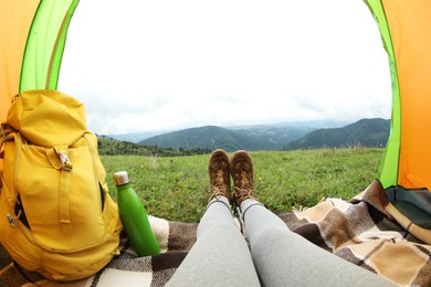 Photo of Woman wearing trekking shoes and lying in tent outdoors, closeup. Fisheye lens effect