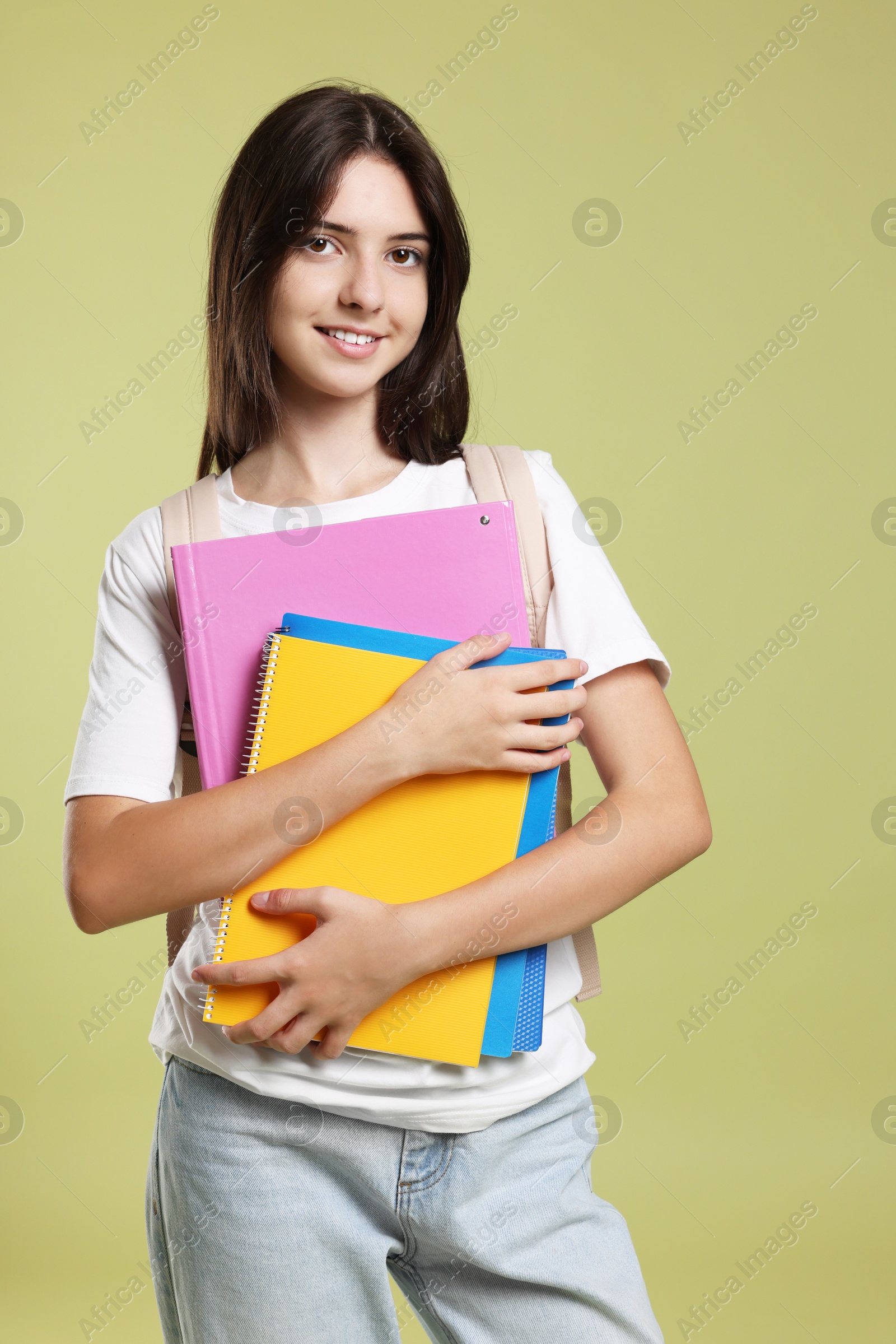 Photo of Portrait of cute teenage girl with backpack and books on olive background