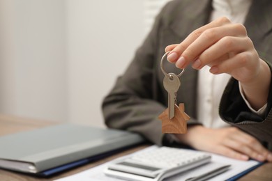 Photo of Real estate agent with house key at table, closeup