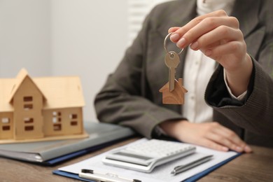 Photo of Real estate agent with house key at table, closeup