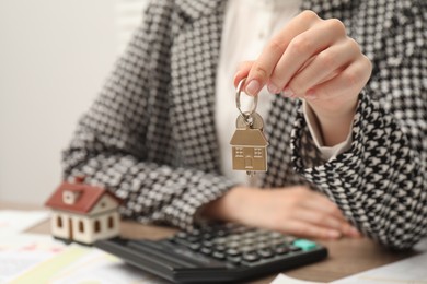 Photo of Real estate agent with house key at table, closeup