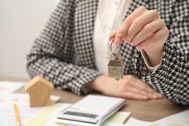 Real estate agent with house key at table, closeup