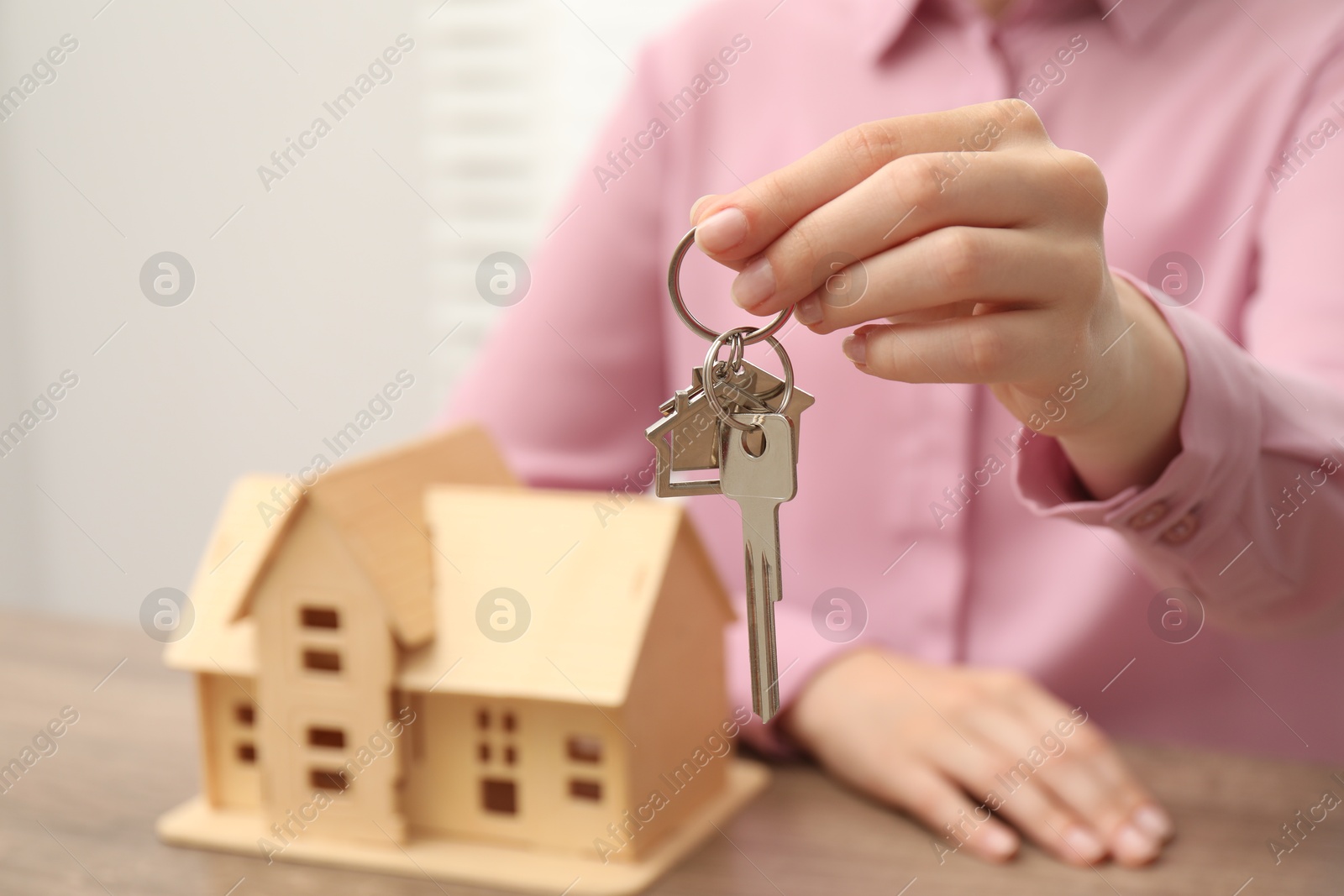 Photo of Real estate agent with house key at table, closeup