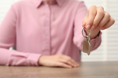 Photo of Real estate agent with house key at table, closeup