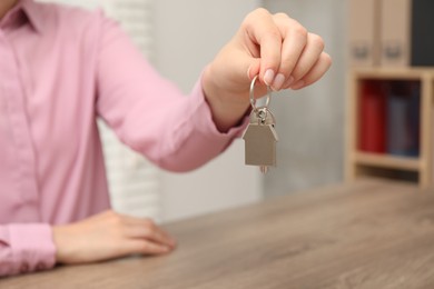 Real estate agent with house key at table, closeup