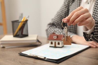 Photo of Real estate agent with house key at table, closeup