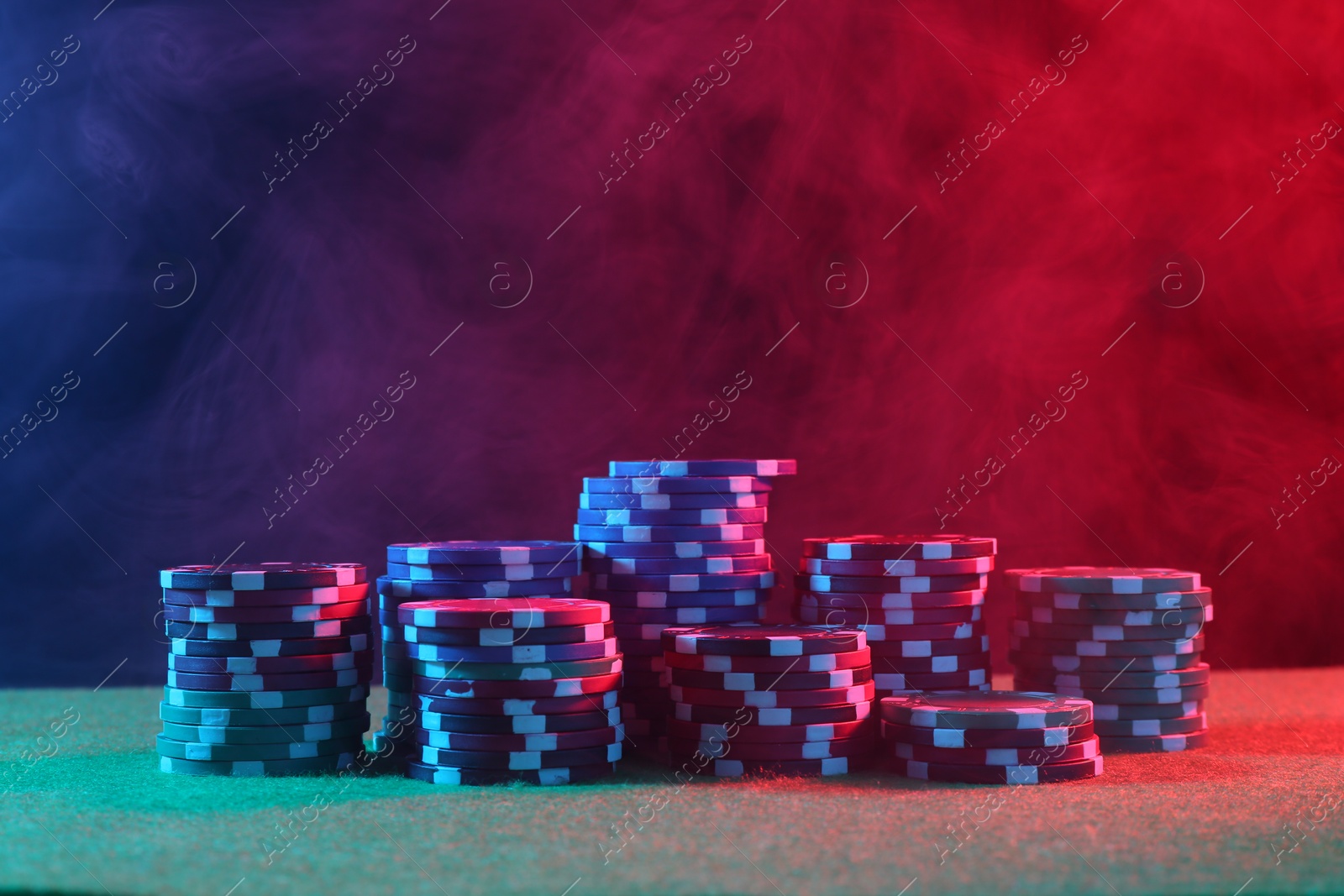 Photo of Poker game. Casino chips on green table in neon lights