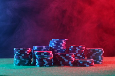 Photo of Poker game. Casino chips on green table in neon lights