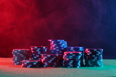 Photo of Poker game. Casino chips on green table in neon lights