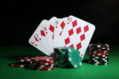 Photo of Poker chips and playing cards on green table