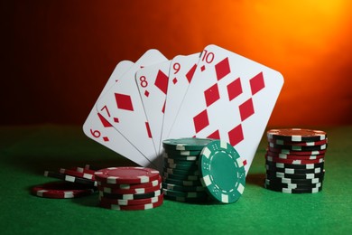 Poker chips and playing cards on green table