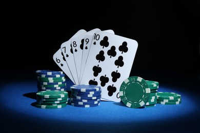 Photo of Poker chips and playing cards on blue table