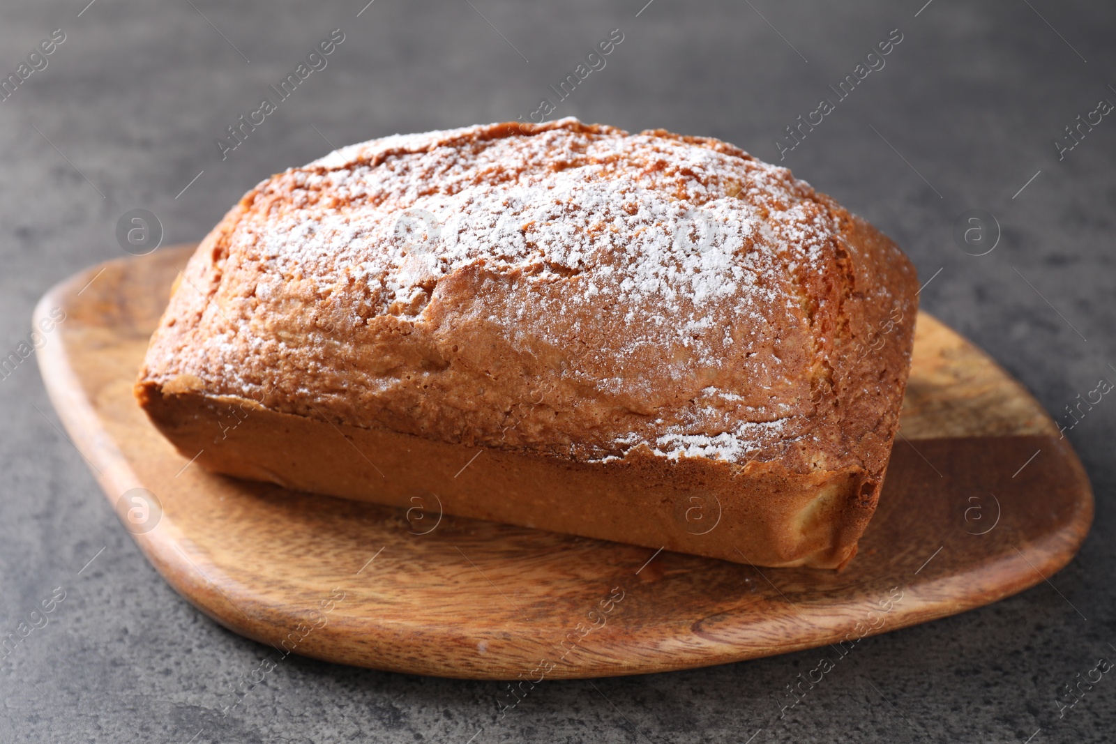 Photo of Tasty sponge cake with powdered sugar on grey table, closeup