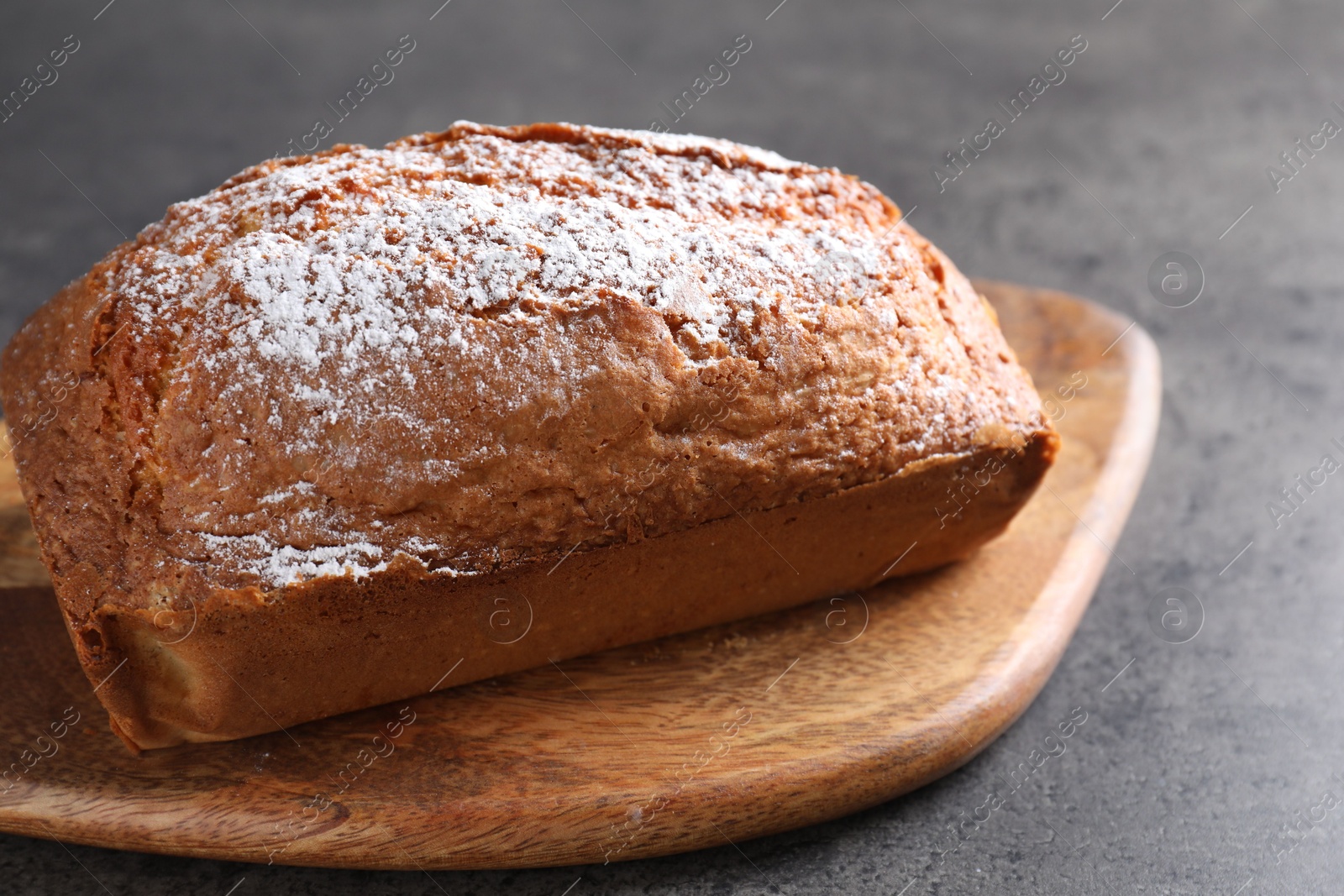 Photo of Tasty sponge cake with powdered sugar on grey table, closeup