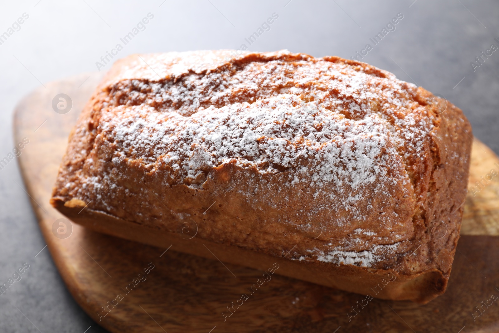 Photo of Tasty sponge cake with powdered sugar on grey table, closeup