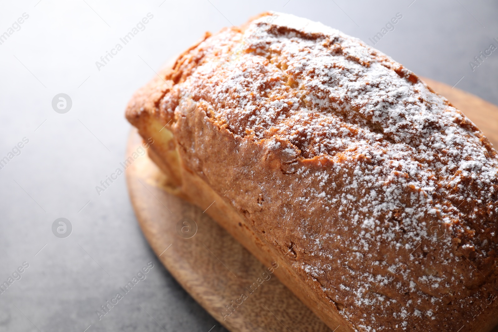 Photo of Tasty sponge cake with powdered sugar on grey table, closeup