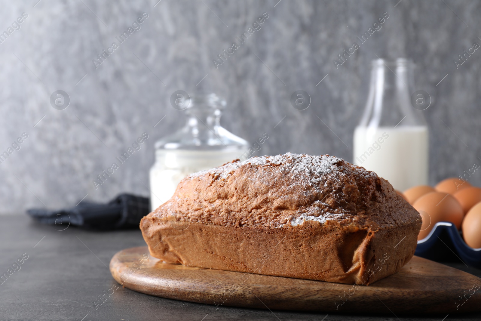 Photo of Tasty sponge cake with powdered sugar on grey table